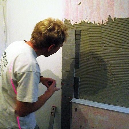 Neubauten - Mitarbeiter fliest eine Wand mit grauen Fliesen